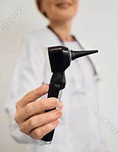 ENT doctor with otoscope in hands standing in audiology office.