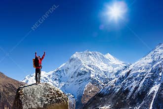 Hiker cheering elated and blissful with arms raised in the sky after hiking to mountain top summit