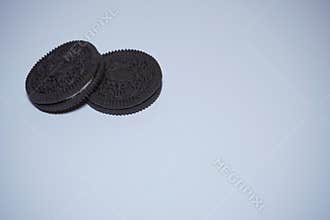 Two black biscuits are placed at the top left on a white background