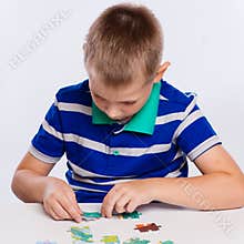Cute little boy playing puzzles at the table