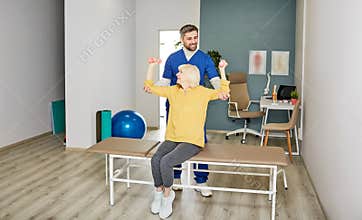 Doctor helps to do therapeutic exercises for a senior woman to improve grannie's health. Elderly woman with dumbbells