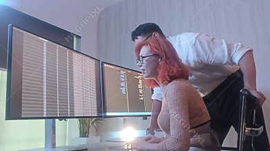 Programmers working at night analyzing code on monitors in a modern office