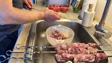 Man Threading Marinated Lamb Meat onto Skewers for Barbecue.