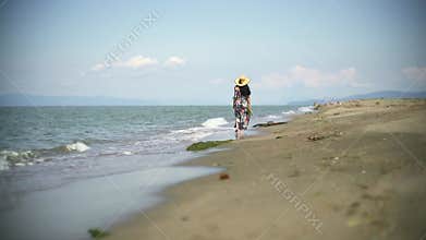 Barefoot woman walks along sandy beach with colorful skirt, sea waves calm summer atmosphere, carries, carries slippers, female