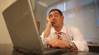 Sleepy businessman using laptop in office