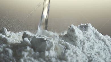 Pouring liquid into a heap of flour while baking