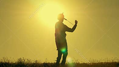 Boy playing with airplane model against orange sunset background