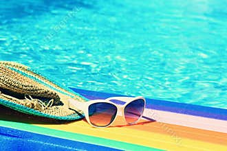 Sunglasses, lilo and hat on the water in hot sunny day. Summer background for traveling and vacation. Holiday idyllic.