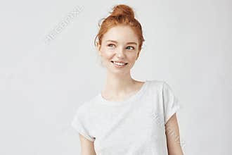 Portrait of playful beautiful ginger girl with freckles smiling.