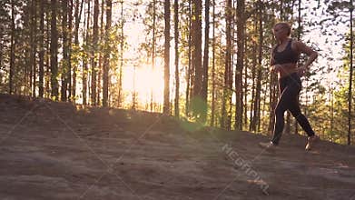 Girl athlete on a morning run. A muscular girl runs uphill at sunrise in the rays of the sun. slow motion