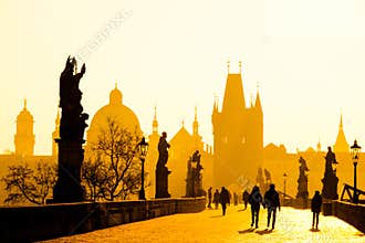 Foggy morning on Charles Bridge, Prague, Czech Republic. Sunrise with silhouettes of walking people, statues and Old