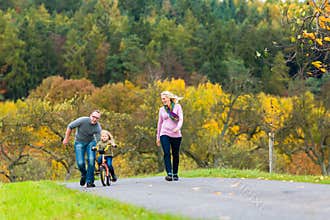 Girl learning bicycling in fall or autumn park