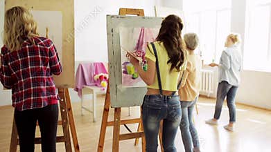 Students with easels painting at art school
