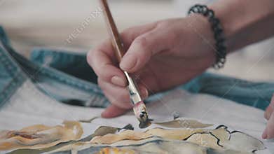 Designer paints with special paints and brushes on the fabric