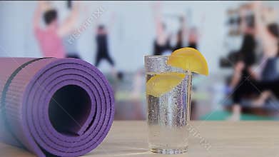 Falling of a slice of a lemon in a glass with water, yoga, pilates, group employment by sports