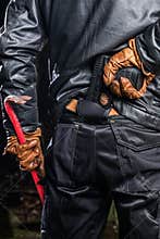Midsection rear view of burglary holding crowbar and gun at nigh