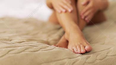 Beautiful woman with bare feet on bed at home