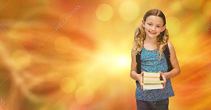 Smiling girl holding books against blur background