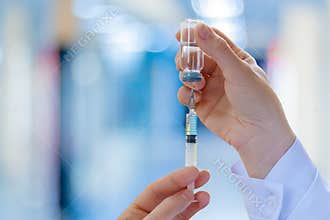 The doctor fills a syringe with vaccine .