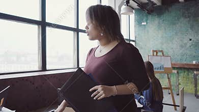 African manager walking through the office and controlling work. Female comes to designers, looks the fabric examples.