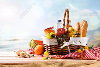 Picnic wicker basket with food on table on the beach