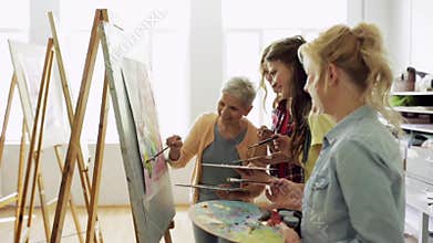 Women with brushes painting at art school