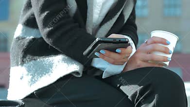 Business woman with a cup of coffee and a mobile phone in the hands