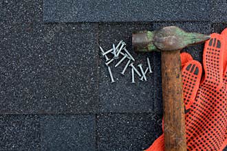 View on Asphalt Roofing Shingles Background. Roof Shingles - Roofing. Asphalt Roofing Shingles Hammer, Gloves and Nails