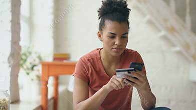 Beautiful happy mixed race woman online banking using smartphone shopping online with credit card at home lifestyle