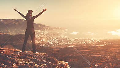 Young woman stand on top of mountain with raised hands