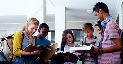 Group of smiling students standing with notebook in corridor