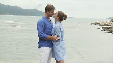 A man strokes a girl by the hair, hugs and kisses her. A pair of lovers rest on the sea