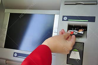 Closeup of womans hand inserting card into ATM