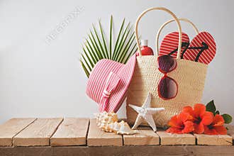 Summer beach bag and hibiscus flowers on wooden table. Summer holiday vacation concept. View from above