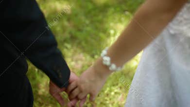 Bride and groom holding hands in summer day