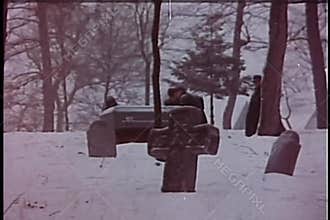 Wide shot of men carrying coffin through cemetery in winter