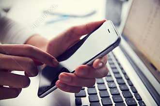 Close Up Of Person At Laptop Using Mobile Phone