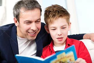 Dad and son reading a book at home
