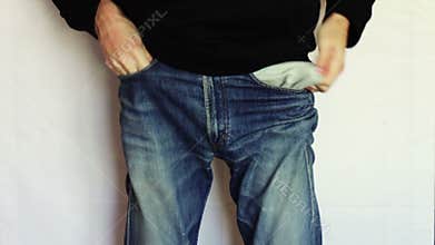 Man turns the empty pockets of his jeans. No money