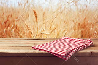 Tablecloth on wooden table over wheat field