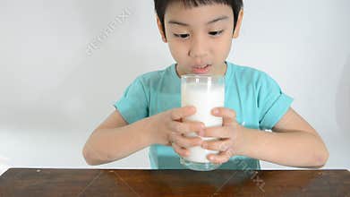 Young Asian boy drinking a glass of milk .
