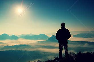Beautiful moment the miracle of nature. Man stands on the peak of sandstone rock in national park Saxony Switzerland and watching