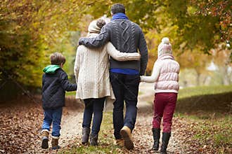 Rear View Of Family Walking Along Autumn Path