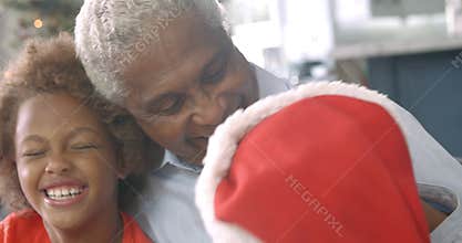 Slow motion sequence of boy and girl sitting on sofa with grandfather at Christmas time