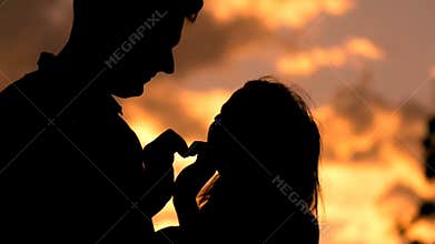 Romantic young couple in love making a heart shape with their hands silhouette