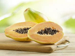 Whole and halved papayas on a wooden board
