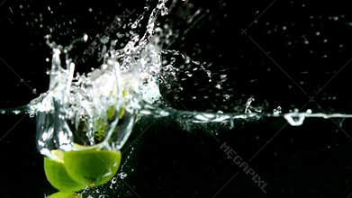 Limes falling in water on black background