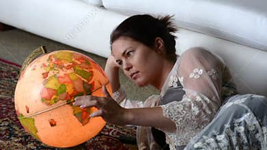 Woman search for a travel destination on a vintage globe