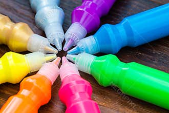 Bottles with colorful dry pigments on wooden background