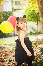 Beautiful little girl dressed as a cat with balloons in hands. Sweet smile, a tender look.